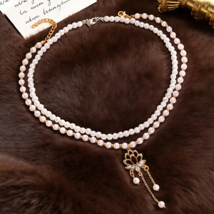 Detailed macro view of a vintage double-layered pearl necklace with a floral gold pendant