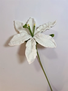 Close-up of a handmade crochet white lily flower with yellow stamens and green stem