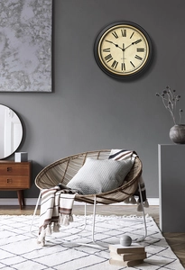 Close-up of vintage wall clock with Roman numerals on dark gray wall in a modern living room