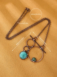Close-up of bohemian bronze ring pendant with green stones on a yellow felt background