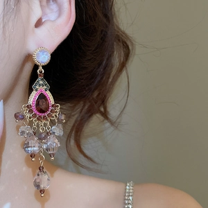 Close-up of vintage tassel earrings with red gemstone and crystals on earlobe