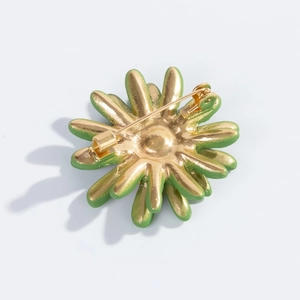 Detail view of the daisy brooch back showing the gold alloy base and pin clasp mechanism