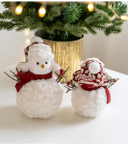 Detail of plush snowman duo with knit scarves and hats near a festive Christmas tree