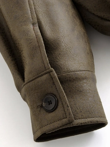 Detail of dark brown vintage faux leather jacket cuff with stitching and button