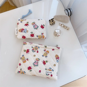 Detailed top view of quilted floral makeup bags with retro cartoon prints on a white table