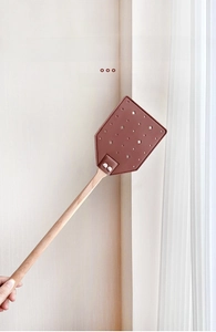 Detail of flower pattern hollow leather fly swatter with a long beech wood handle