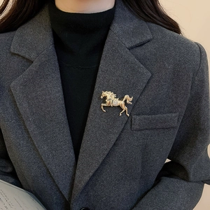 Golden horse brooch with rhinestones worn on a charcoal grey suit lapel closeup