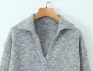Gros plan d'un pull en maille grise avec col en V élégant sur un cintre en bois
