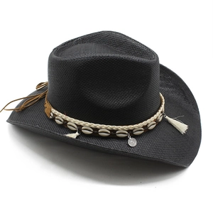 Détail du chapeau de cowboy en paille noire avec décor coquillages et pompons