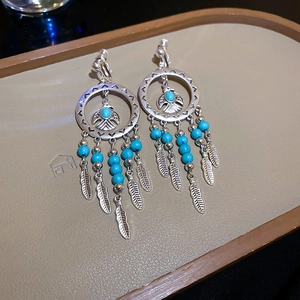 Detail of bohemian silver eagle clip-on earrings with blue beads and metal feathers
