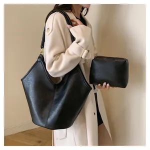 Elegant black grained faux leather tote bag with matching pouch shown on a model