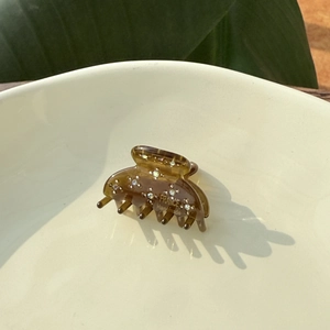 Close-up of amber acetate hair claw clip with rhinestones and gold handmade lettering