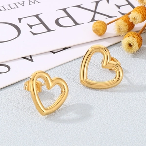 Vue détaillée de boucles d'oreilles cœur dorées sur une surface texturée bleu clair