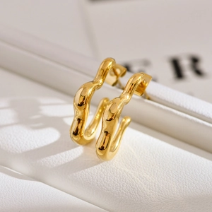 Detailed macro view of irregular wavy gold-plated stainless steel earrings on leather