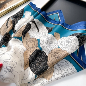 Detailed view of striped silk-like scarf with floral pattern on a black tray