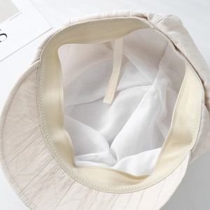 Detailed interior of a beige sun hat showing adjustable drawstrings and soft texture