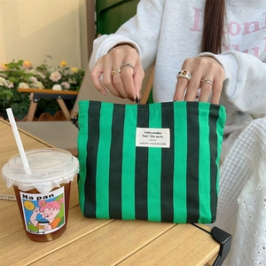 Detail of green and black striped canvas cosmetic bag with metal zipper and woven label