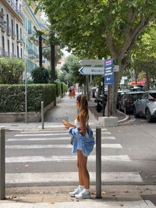 Street style view of striped blue shirt with white shorts and metallic silver sneakers