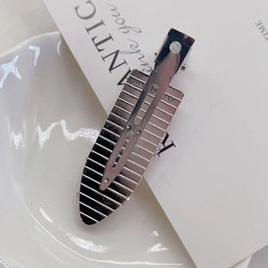 Detail of silver metal hair clip back with engraved Made in Japan text on a white dish