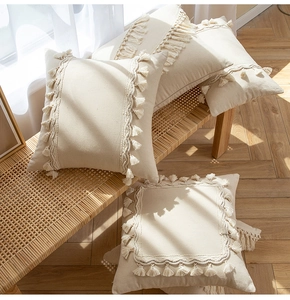 Detail of cream tassel pillow covers with bohemian fringe on a woven bench