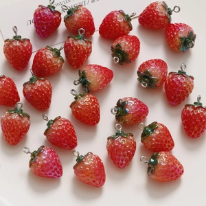 Close-up of pearlescent resin strawberry charms with metal rings for DIY jewelry making