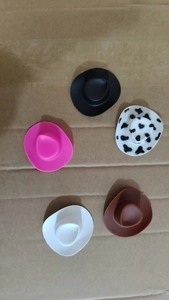 Miniature colorful plastic cowboy hats in black, pink, cow print, and brown for party decor