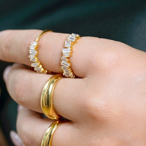 Close-up of elegant gold stacked rings with rectangular cubic zirconia on a model's hand