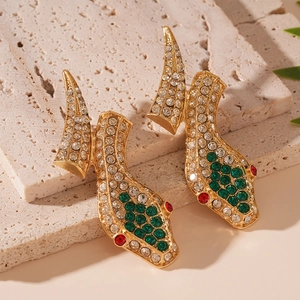Detailed view of snake head earrings with sparkling green and clear crystals in gold setting