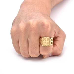 Detailed view of a men's gold stainless steel ring with embossed cross patterns on the finger
