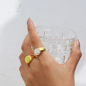 Detail of 18k gold plated sunburst signet rings with white and green enamel on hand