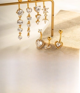 Detailed macro view of gold-plated titanium steel belly rings with cubic zirconia charms