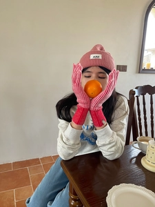 Detalle del tejido suave del gorro rosa de invierno y guantes a rayas para mujer
