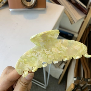 Close-up of a large acetate hair claw clip with yellow marble pattern texture