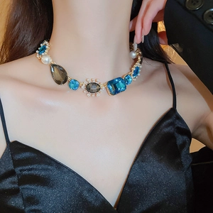 Detail of vintage necklace with gold chain, blue gems, and pearls on a model
