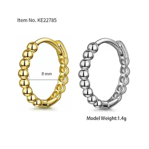 Detail of 8mm bead huggie earrings in gold and silver finish with hinged closure