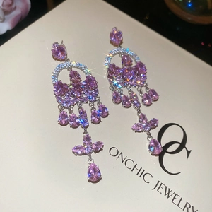 Detail of luxury long tassel earrings with pink-purple gemstones and silver base