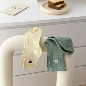 Detail of cream and sage green crew socks with dot yarn texture and logo embroidery