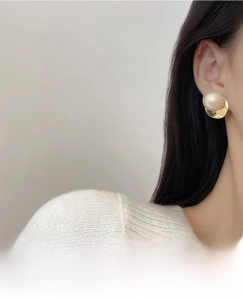 Detail of elegant gold twist circle earring with pearl on model for a french style look