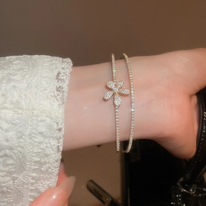 Detailed view of a gold double-layer floral bangle with sparkling zircon pavé on the wrist