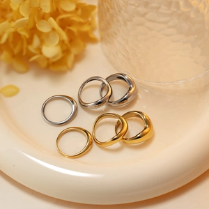 Minimalist 18K gold and silver wavy stainless steel rings set on ceramic tray