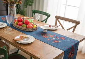 Detail view of the deep blue table runner with floral patterns on a wooden dining table