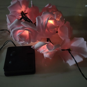 Pink LED rose string lights glowing with warm light and black battery box for outdoor decor