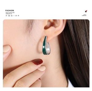 U-shaped geometric silver earrings with dark green enamel finish on female model