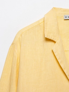 Detail of a bright yellow linen shirt showing fabric texture and collar stitching