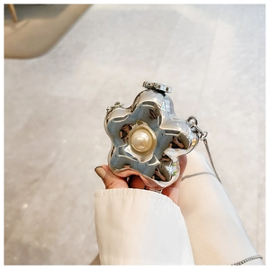 Detailed macro view of a silver flower-shaped mini bag with a large central pearl accent