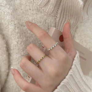 Close-up of gold and silver sterling silver rings with emerald green stones on knitwear