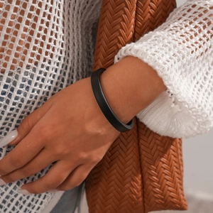 Detail of a black irregular geometric acrylic open cuff bracelet on a female wrist
