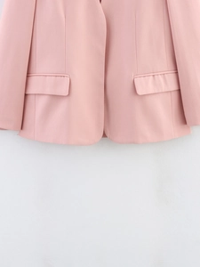 Dettaglio del blazer rosa che mostra tasche laterali simmetriche e orlo arrotondato