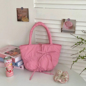 Chic pink quilted tote bag with cute bow detail, shown in a cozy natural light setting