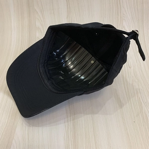 Black cotton baseball cap with adjustable metal buckle on light wood table